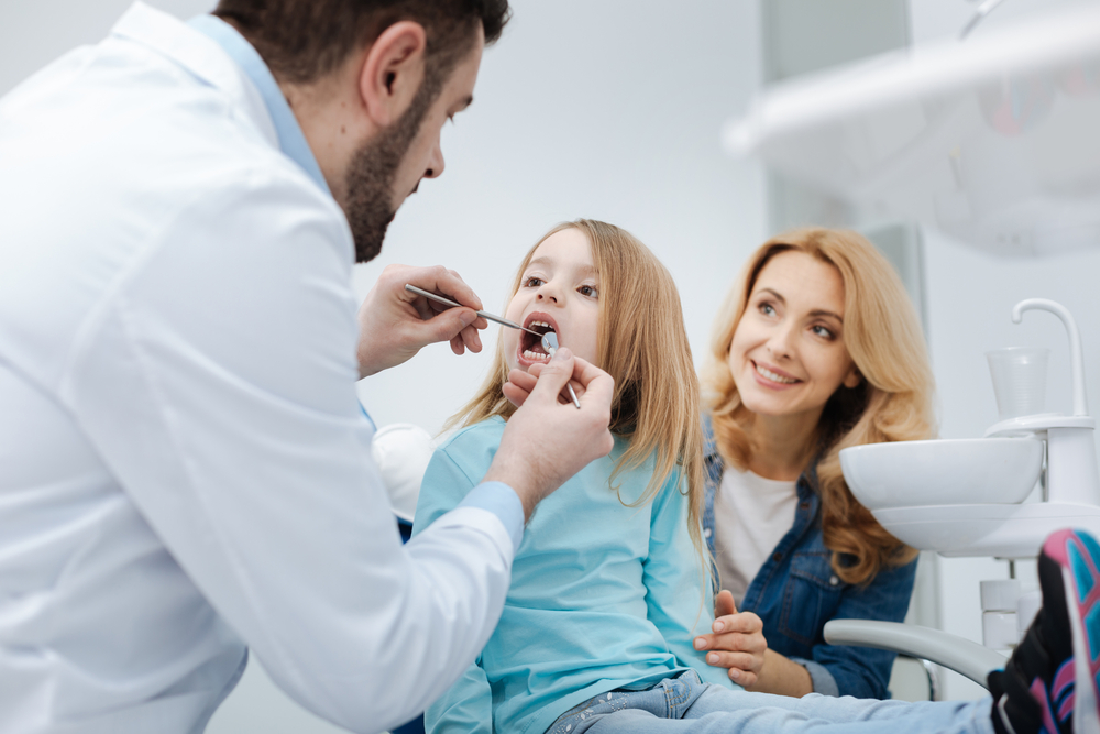 child getting a dental exam while mother watches / dentist in Franklinville, NJ